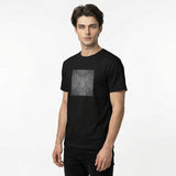 Front-left view of a black men’s t-shirt by HOLO streetwear. Scratchy Lines features a square in the center of the chest. In a dark grayscale, the design looks like a surface has been scratched diagonally, symmetrically and mirrored. Minimalist style.