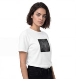 Front-right view of a white women’s t-shirt by HOLO streetwear. Scratchy Lines features a square in the center of the chest. In a dark grayscale, the design looks like a surface has been scratched diagonally, symmetrically and mirrored. Minimalist style.